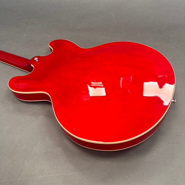 Glossy red semi-hollow body electric guitar back with cream binding on a gray background