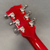 Back view of red guitar headstock with six chrome tuning pegs on gray background