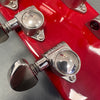Close-up of chrome Grover tuning peg on red guitar headstock with glossy finish