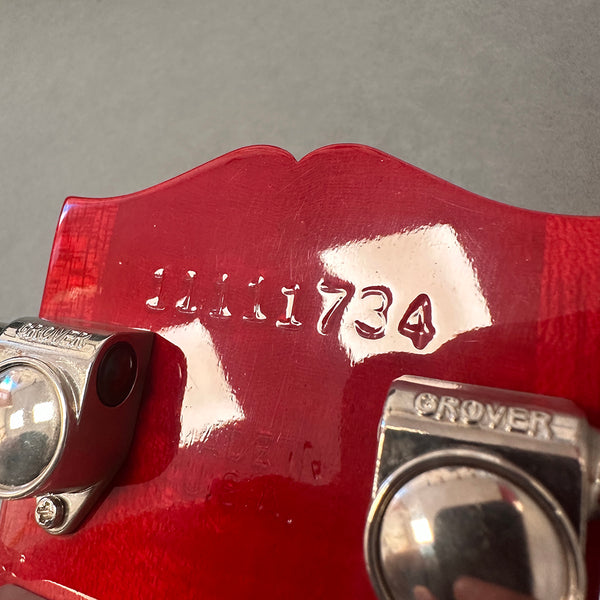Close-up of red guitar headstock showing serial number 1111734 and Grover tuning pegs