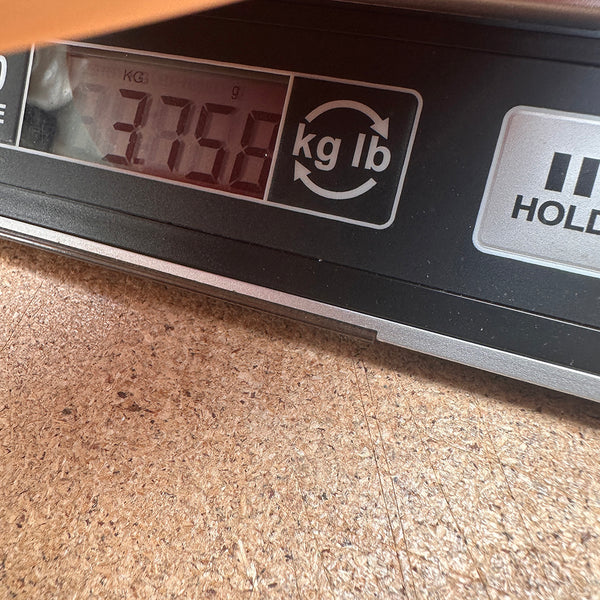 Digital scale displaying guitar weight of 3.758 kilograms on a wooden surface at Coffee House Guitars