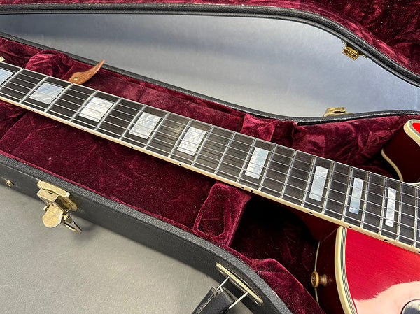 Close-up of electric guitar fretboard with rectangular pearl inlays inside red velvet-lined black hard case at Coffee House Guitars.