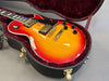 Sunburst electric guitar with dual humbucker pickups in a plush red-lined hard case, close-up of body and bridge.