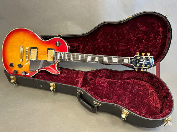 Gibson Les Paul electric guitar in sunburst finish with humbucker pickups inside open black hard case with red velvet interior lining