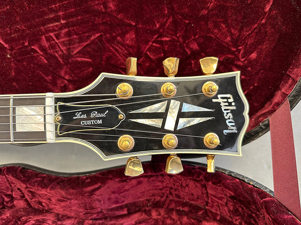 Gibson Les Paul Custom guitar headstock with gold tuning pegs and mother of pearl inlays inside red velvet guitar case