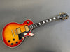 Vintage sunburst electric guitar with dual humbucker pickups and black pickguard on gray background