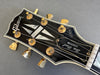 Close-up of Gibson Les Paul Custom guitar headstock with gold tuning pegs and black finish