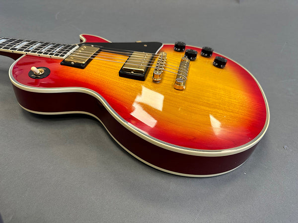 Sunburst electric guitar with gold humbucker pickups and black pickguard on gray background