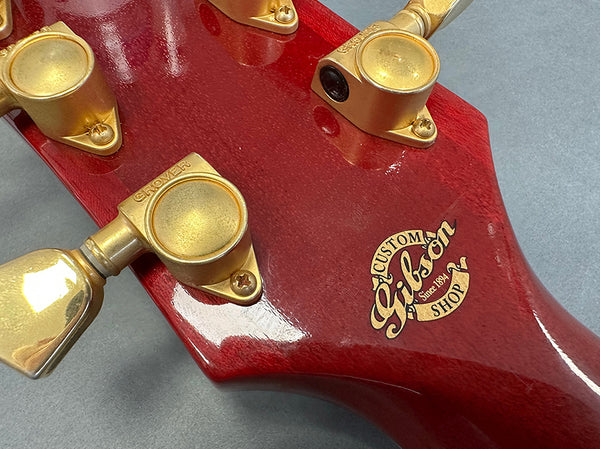 Close-up of red Gibson Custom Shop guitar headstock with gold Grover tuning pegs and Gibson Custom Shop logo badge