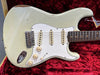 Vintage white electric guitar with three single-coil pickups and rosewood fretboard on red plush case interior