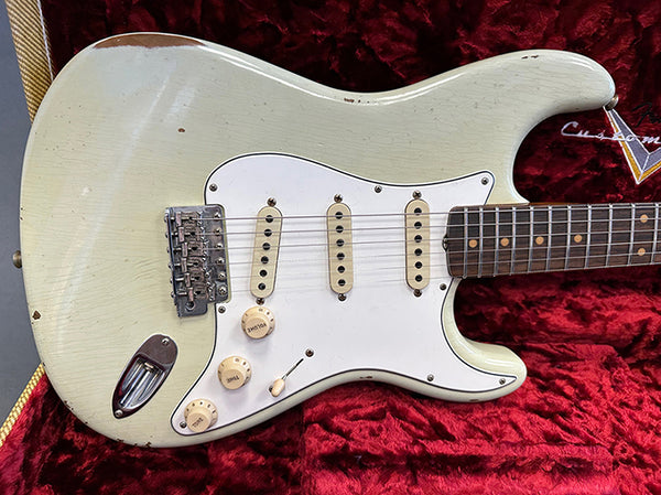 Vintage white electric guitar with three single-coil pickups and rosewood fretboard on red plush case interior