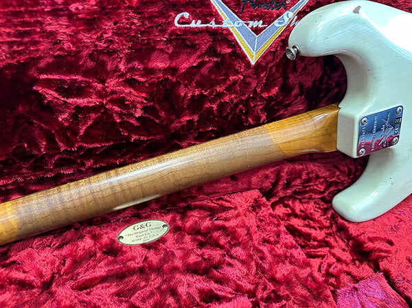 Back view of a white Fender Custom Shop electric guitar with a figured maple neck resting on a red velvet-lined guitar case with Fender Custom Shop logo and G&G Craftsman Warranty badge.