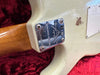 Close-up of Fender Limited Edition electric guitar neck plate with serial number on a vintage white guitar body resting on a red plush surface
