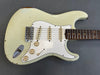 Vintage white worn electric guitar with three single-coil pickups and rosewood fretboard on gray background