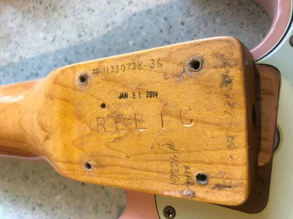 Close-up of guitar neck heel showing serial number 11330728-36, date stamp JAN 31 2014, and the word RELIC engraved on the wood.