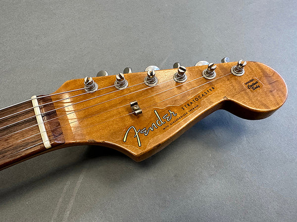 Close-up of Fender Stratocaster guitar headstock with vintage brown finish and six tuning pegs on gray background