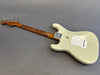 Vintage white electric guitar with worn finish and figured maple neck, laid flat on gray background, back view