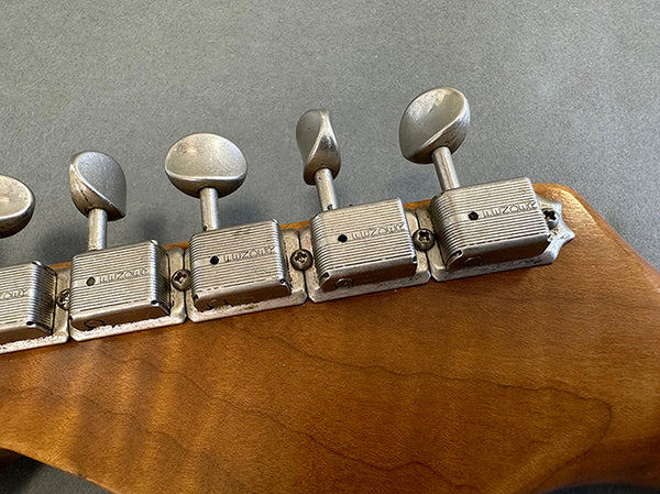 Close-up of vintage Kluson tuning pegs on wooden guitar headstock for precise string tuning at Coffee House Guitars.