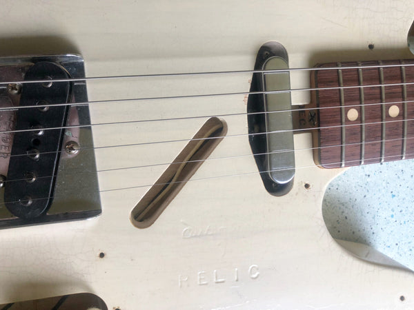 Close-up of white vintage relic electric guitar body showing worn finish, metal bridge, single coil pickups, and rosewood fretboard with dot inlays