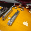 Close-up of sunburst electric guitar body showing chrome bridge, strings, white toggle switch, and amber control knobs with volume markings, inside a velvet-lined case.