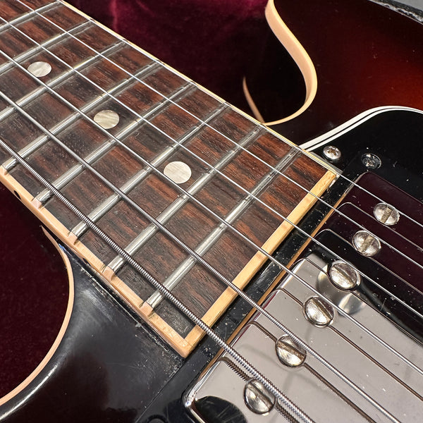 Close-up of electric guitar fretboard and chrome humbucker pickup with metal strings on black guitar body