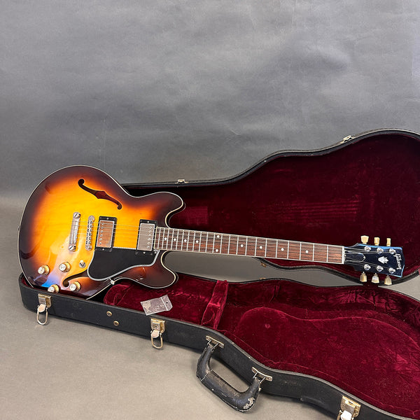 Gibson ES-335 semi-hollow electric guitar in sunburst finish with rosewood fretboard, displayed in open black guitar case with red velvet interior.