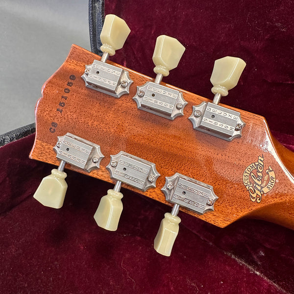 Close-up of Gibson Custom Shop guitar headstock back with vintage tuning pegs and serial number on mahogany wood in red velvet case