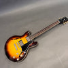 Gibson semi-hollow electric guitar in sunburst finish with dual humbucker pickups and rosewood fretboard on gray background