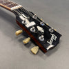 Close-up of Gibson guitar headstock with tuning pegs and logo on matte gray background