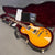 Gibson Les Paul electric guitar with sunburst finish inside open black hardshell guitar case with burgundy velvet interior and certificate of authenticity