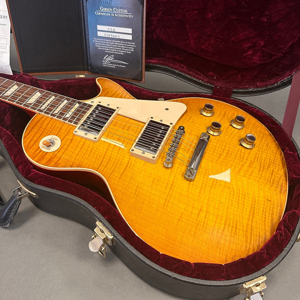 Gibson Les Paul electric guitar with sunburst finish, cream pickguard, chrome hardware, and humbucker pickups in open black hard case with red interior lining and certificate of authenticity