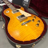 Gibson Les Paul electric guitar with honey burst finish, curly maple top, cream pickguard, and humbucker pickups in velvet-lined hardshell case