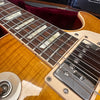 Close-up of vintage electric guitar fretboard with rectangular inlays and chrome humbucker pickups on amber sunburst body