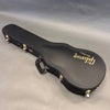 Black Gibson guitar hard case with gold latches and handle on gray background