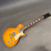 Gibson Les Paul electric guitar with sunburst finish, dual humbucker pickups, rosewood fretboard, and cream pickguard on gray background