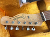 Close-up of Fender Custom Telecaster guitar headstock with six tuning pegs and strings on a yellow plush case lining