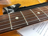 Close-up of rosewood guitar fretboard with metal frets and white dot inlays, guitar strings in focus on wooden background