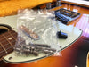 Bag of metal bridge screws on sunburst electric guitar body with white pickguard and rosewood fretboard close-up