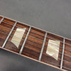 Close-up of guitar fretboard with pearl trapezoid inlays and steel strings on rosewood fingerboard