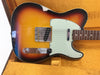 Fender Telecaster electric guitar with sunburst finish and white pickguard in vintage orange guitar case