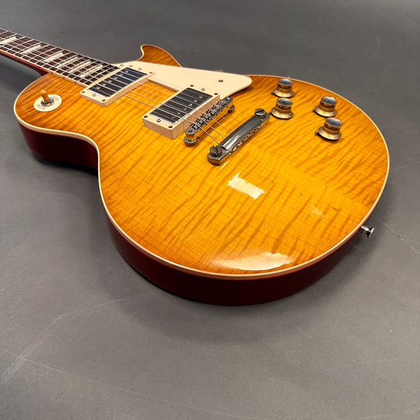 Electric guitar with sunburst flame maple top, dual humbucker pickups, chrome bridge, cream pickguard, and wooden control knobs on dark gray background