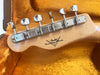 Close-up of Fender Custom Shop guitar headstock with vintage tuning pegs in orange plush guitar case interior