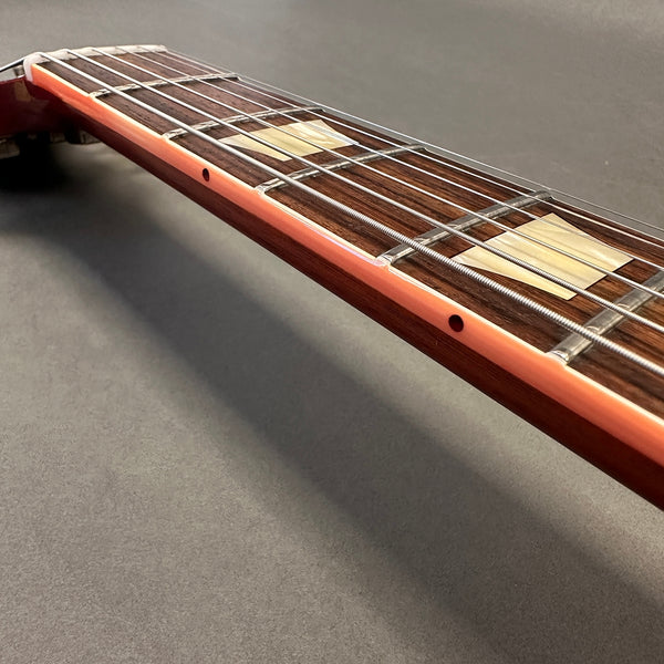 Close-up of guitar neck and fretboard showing strings, fret markers, and side dot inlays on wooden fingerboard