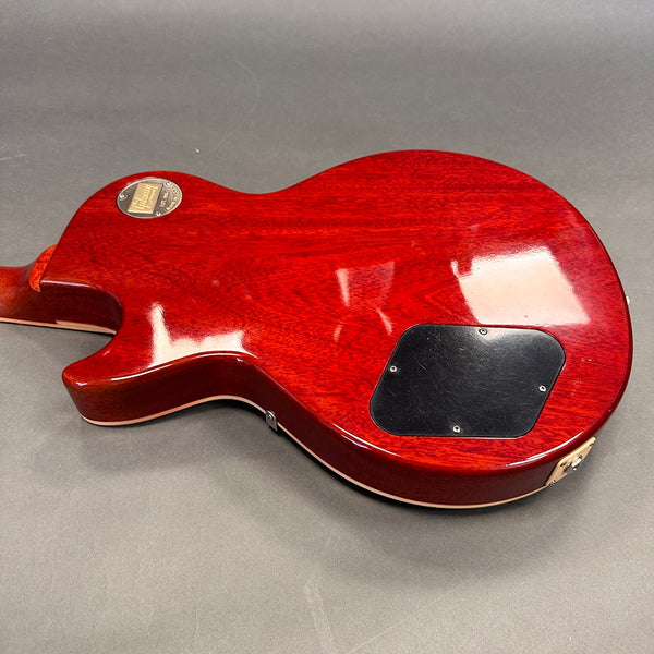Back side view of cherry red electric guitar body with black control cover plate and vintage Gibson Custom Shop metal badge