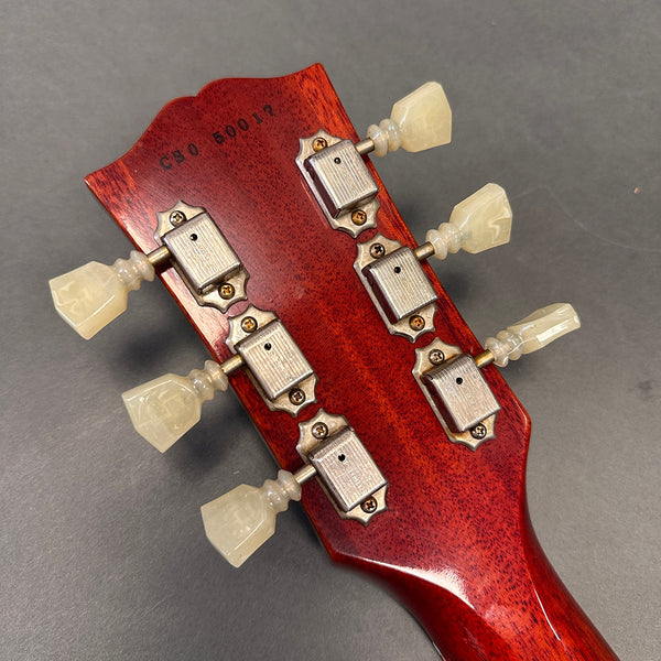Back of guitar headstock showing vintage-style tuning pegs with cream plastic buttons and serial number C80 50017 on reddish wood finish
