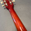 Close-up of the back of a polished mahogany guitar neck with vintage-style tuning pegs on a gray background