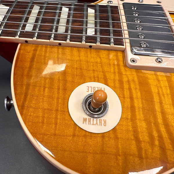Close-up of honey burst electric guitar body showing toggle switch and rosewood fretboard with double block inlays
