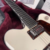Close-up of white electric guitar with black fretboard and metal pickup in plush burgundy guitar case interior