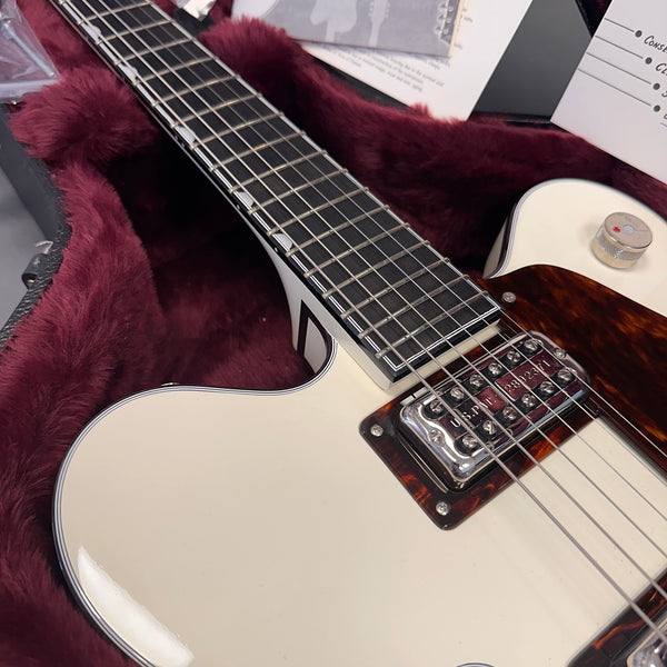 Close-up of white electric guitar with black fretboard and metal pickup in plush burgundy guitar case interior