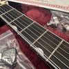 Close-up of acoustic guitar fretboard with steel strings, plastic guitar tool, and metal strap buttons in protective plastic bags on red plush guitar case lining